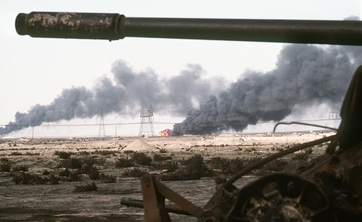 A Kuwaiti oil field set afire by retreating Iraqi troops burns in the distance beyond an abandoned Iraqi T-55A tank following Operation Desert Storm.